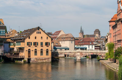 Buildings by river against sky in city