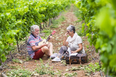Smiling senior couple enjoying amidst grape plants at vineyard
