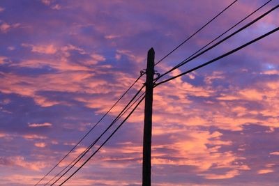 Low angle view of electricity pylon against cloudy sky