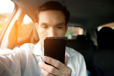Mid adult man using mobile phone while sitting in car