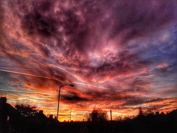 Silhouette of electricity pylon against dramatic sky