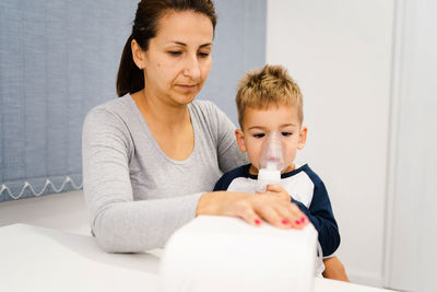 Mother sitting with son wearing oxygen mask