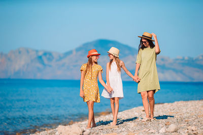 Full length of mother with daughters walking on beach