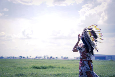 Woman with umbrella on field against sky