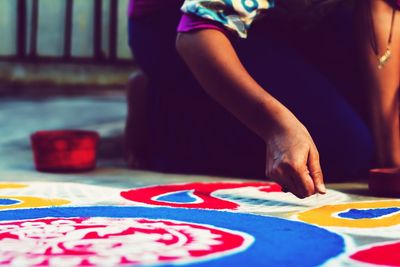 Midsection of woman making colorful rangoli