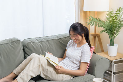 Young woman sitting on sofa at home