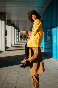 From below of modern african american guy in sunglasses and jacket carrying trendy black girlfriend on shoulders standing on street looking at camera