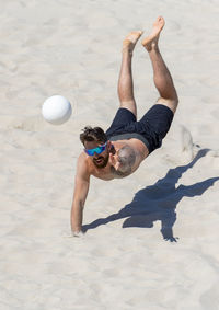 Shirtless man playing volleyball at beach