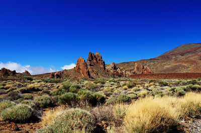 Rock formations on landscape at el teide national park against clear blue sky