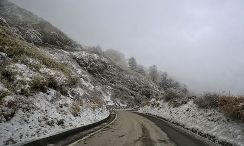 Road amidst snow covered mountains against sky