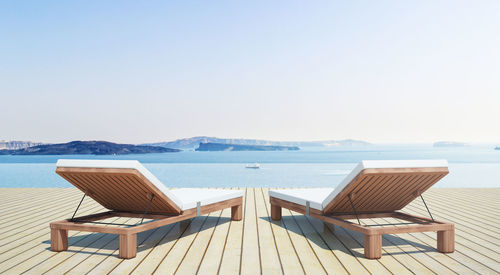 Chaise longue by sea against sky