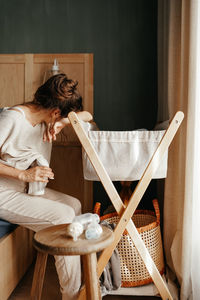 Rear view of woman sitting on chair at home