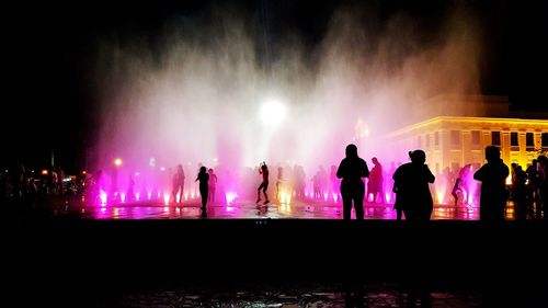 Silhouette people enjoying at illuminated fountain during concert