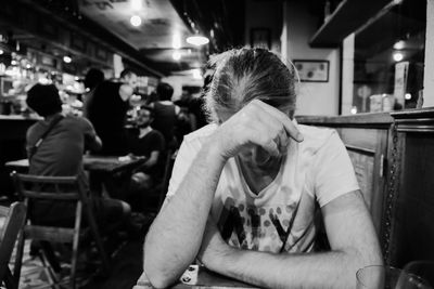Depressed man sitting at table in bar