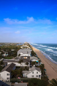 High angle view of buildings by sea against blue sky