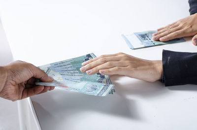 Close-up of hand holding paper against white background