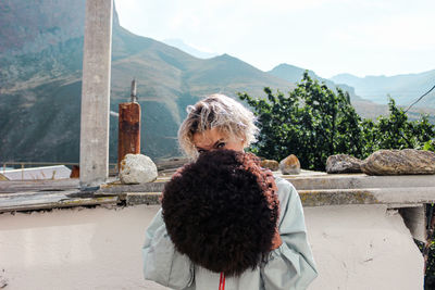 Portrait of woman covering face with wig outdoors