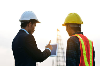 Side view of people working against clear sky