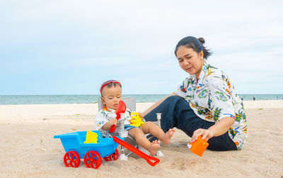 Happy boy with toy on beach against sky