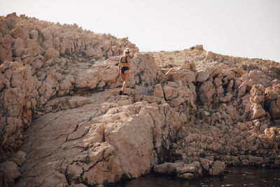 Full length of woman walking on rock against sky