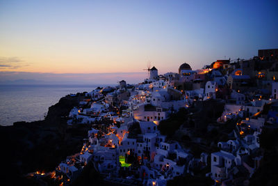 High angle view of townscape by sea against sky at sunset