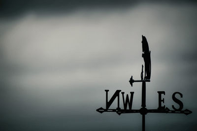 Low angle view of weather vane against sky