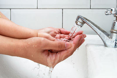 Cropped hand of woman in bathroom at home