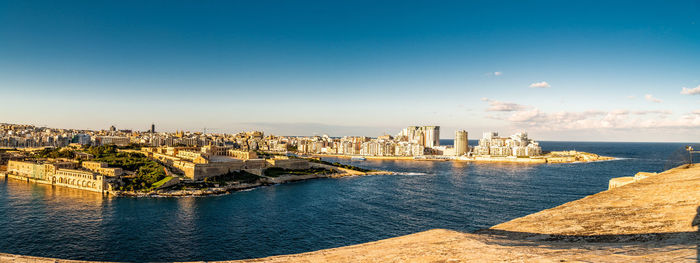 Panoramic view of sea and buildings against blue sky