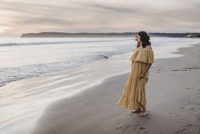 Woman standing on beach by sea against sky