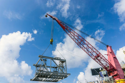 Low angle view of cranes at construction site against sky