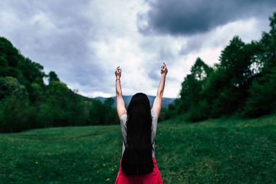 Rear view of woman standing by plants against sky