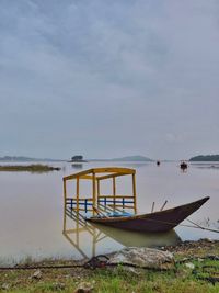 Boat moored on lake against sky