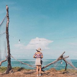 Woman standing by sea against sky