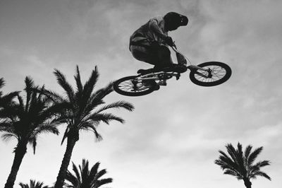 Low angle view of mountain biker in mid-air against sky