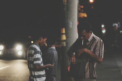 People standing on street in city at night
