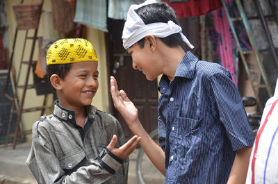 Happy friends gesturing while standing outdoors