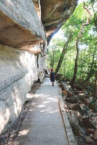 Woman walking by rocks in forest