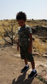 Boy standing on field against clear sky