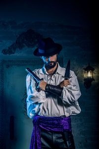 Full length of young man holding hat at night