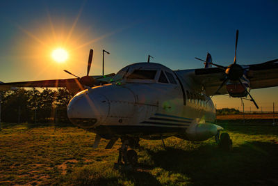 Airplane on field against sky during sunset