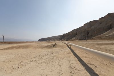 Dirt road in desert against clear sky