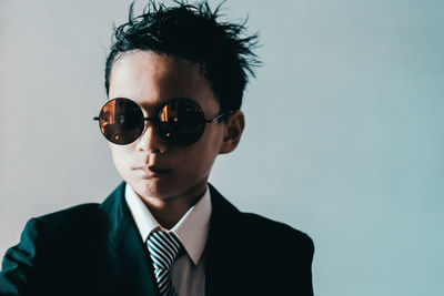 Boy wearing sunglasses against blue background
