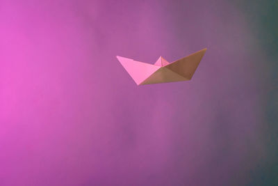 Close-up of paper boat with smoke against pink background