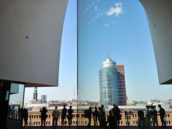 Group of people in city buildings against sky