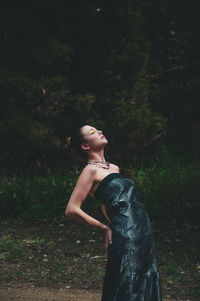 Side view of young woman looking up in forest