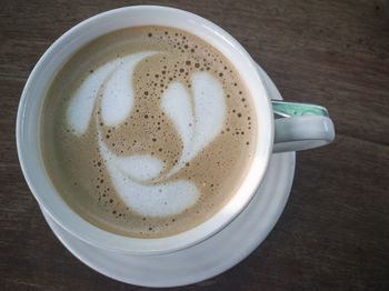 Latte coffee in a white cup on a wooden table