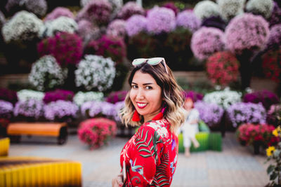 Portrait of smiling woman standing against pink flowers