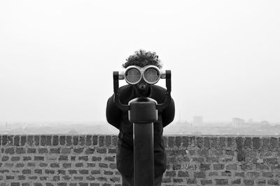 Portrait of man looking through coin-operated binoculars at observation point