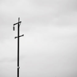 Low angle view of silhouette telephone pole against sky