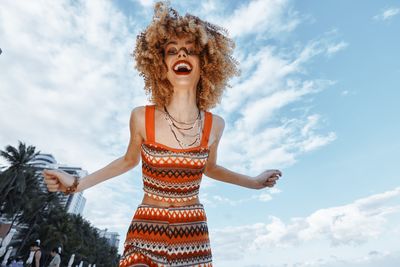 Young woman standing against sky